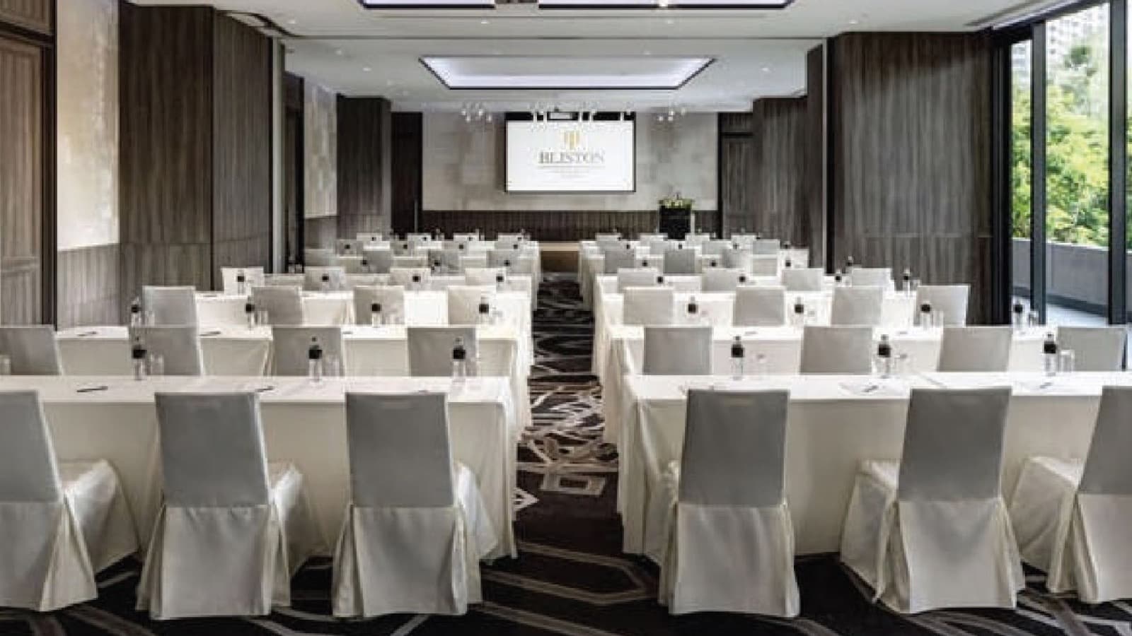 A hotel meeting room in classroom layout with white-covered chairs