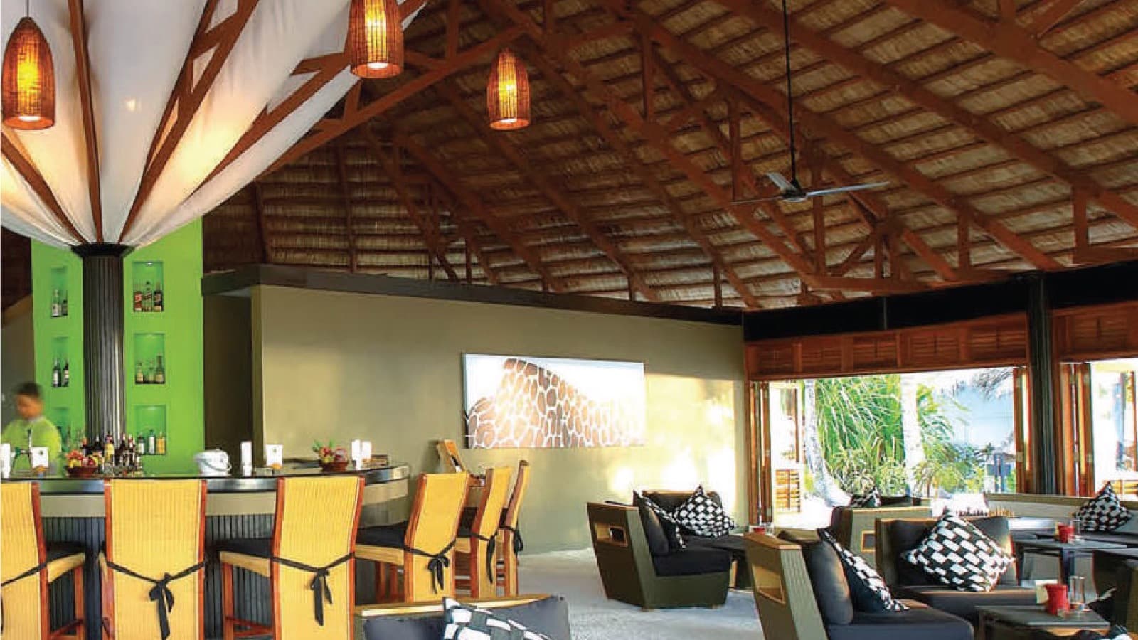 An open-air resort lounge furnished with synthetic rattan sofas and chairs